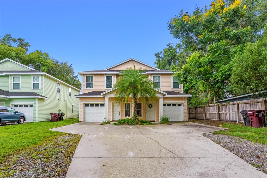 A two-story duplex with light orange siding, two garage doors, and a central palm tree — 2544 MAYER STREET, ORLANDO, FL