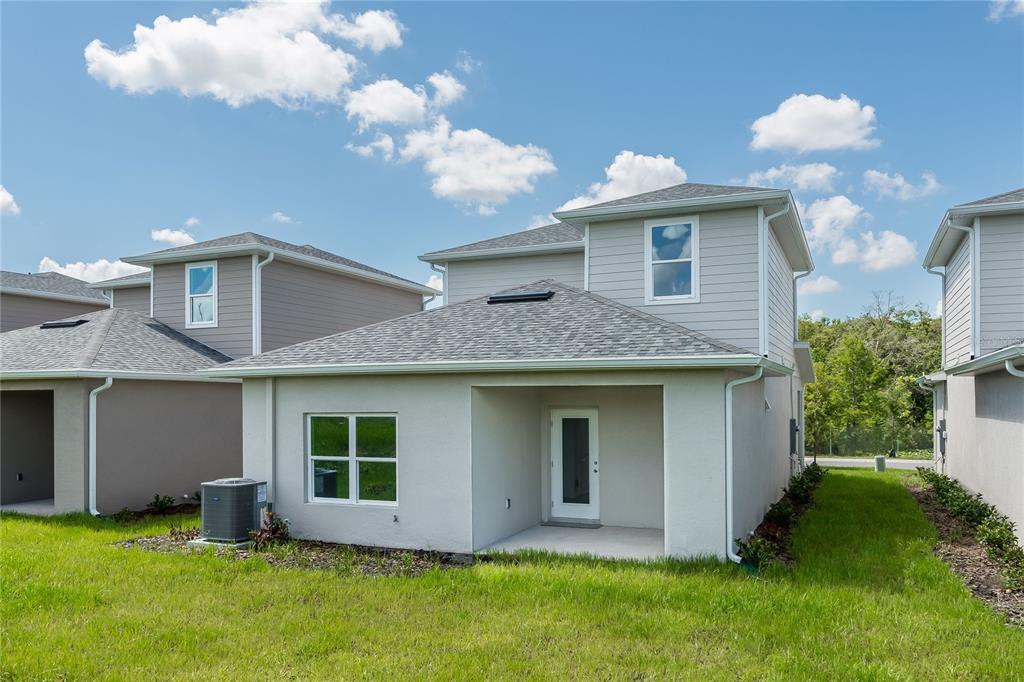 The exterior rear view of a two-story house features a small patio and yard — 5341 VISTA LAGO DRIVE, ORLANDO, FL