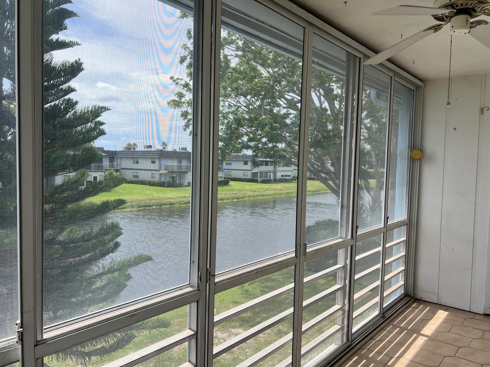 A screened-in porch overlooks a canal with apartment buildings in the background — 424 Saxony, Delray Beach FL 33446, DELRAY BEACH, FL