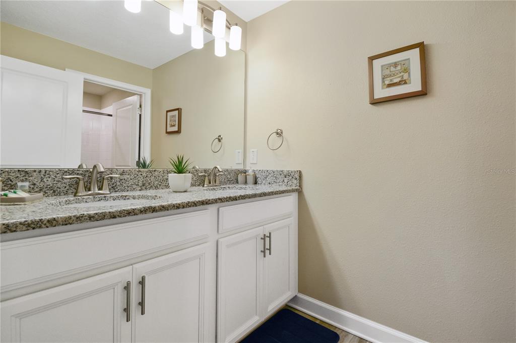 A bathroom features a double vanity with granite countertops, white cabinets, and a large mirror — 3079 TOM SAWYER DRIVE, KISSIMMEE, FL