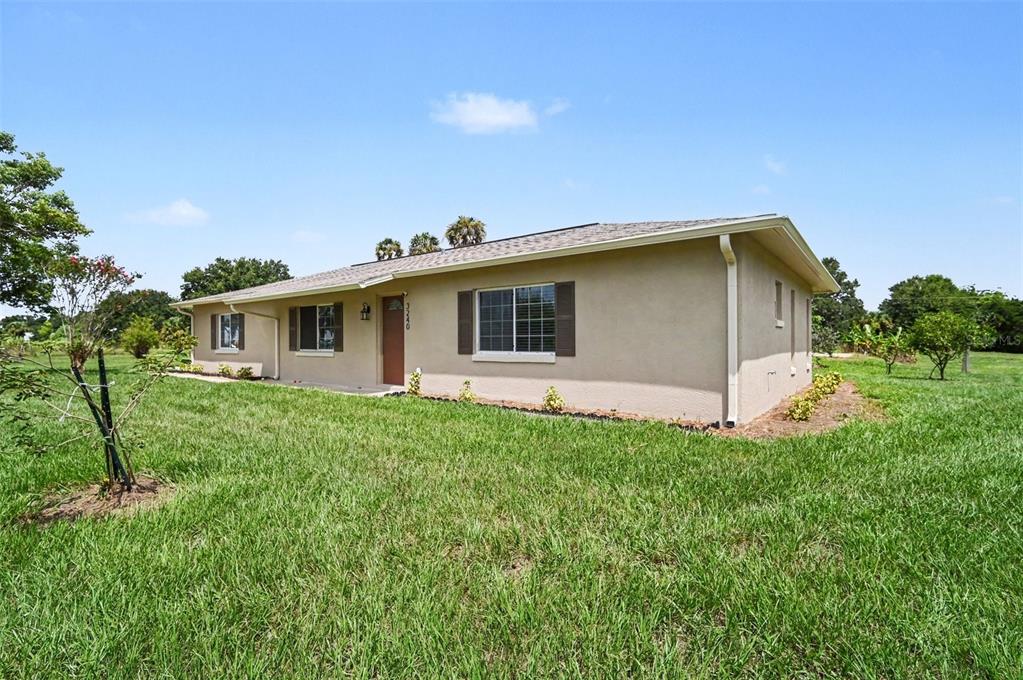 A single-story house with tan stucco siding, a brown roof, and brown window shutters — 3240 CORAL AVENUE, MIMS, FL