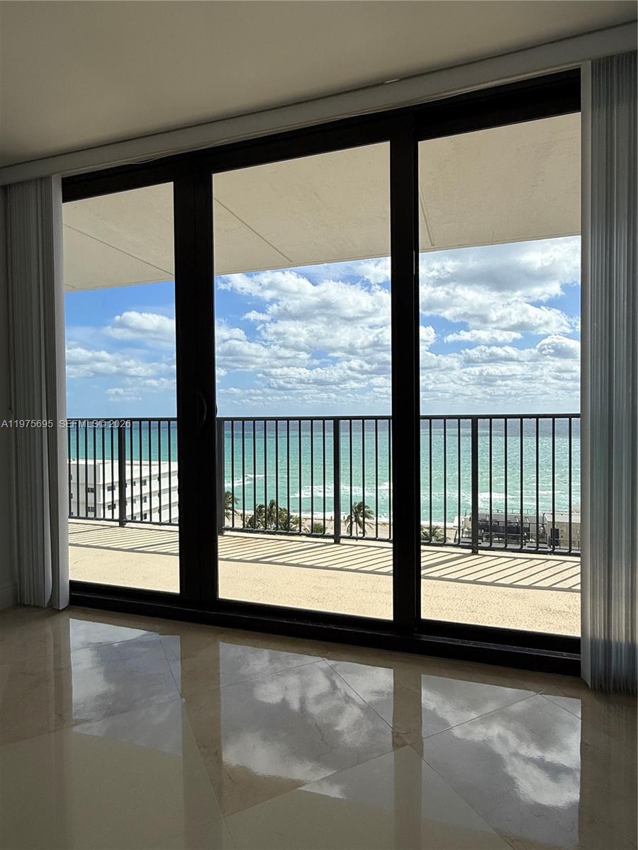 A room with light-colored tile flooring features large sliding glass doors overlooking a beach — 2101 S Ocean Dr # 1201, Hollywood FL 33019, HOLLYWOOD, FL