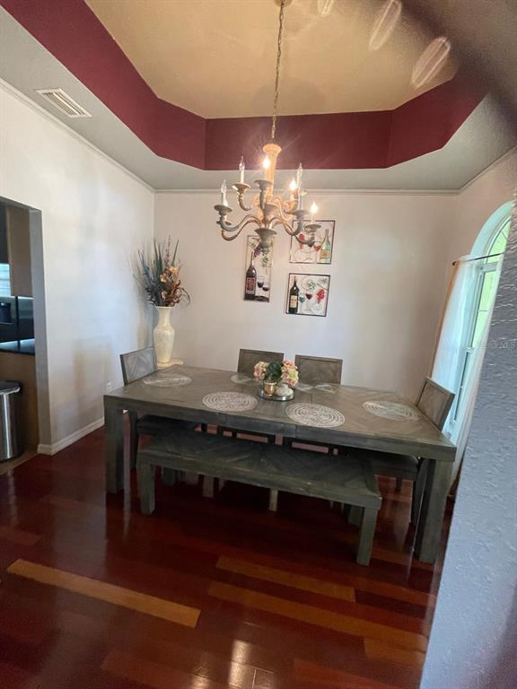 A dining room features a wooden table with a bench, chairs, and a chandelier — 4005 CHELSEA LANE, LAKELAND, FL