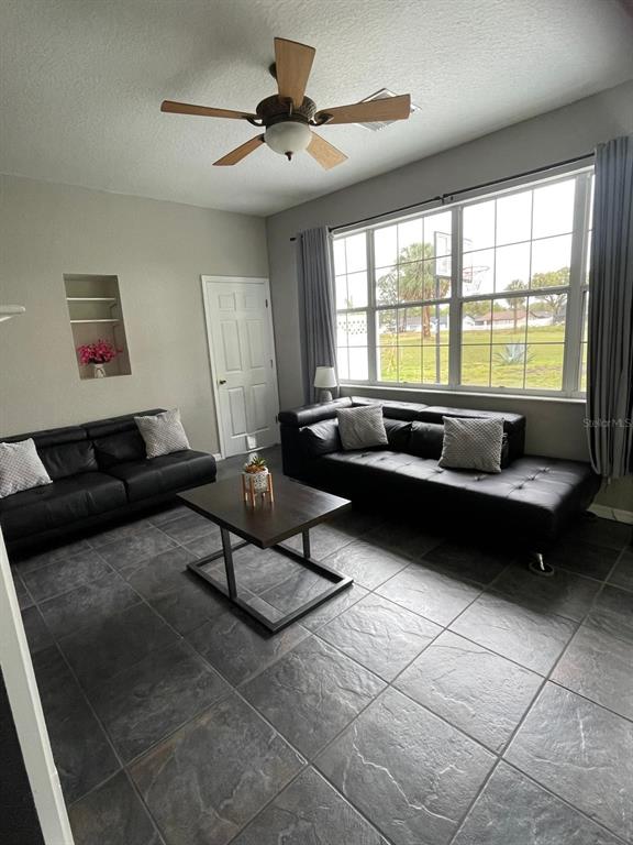 A living room features two black leather sofas, a coffee table, and large windows — 4005 CHELSEA LANE, LAKELAND, FL