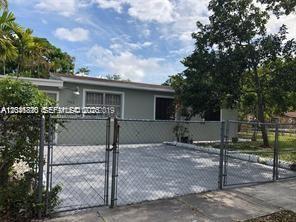 A single-story house with a gray exterior and a fenced-in gravel driveway — 1575 NW 127th St, North Miami FL 33167, NORTH MIAMI, FL
