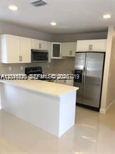 A kitchen with white cabinets, stainless steel appliances, and a white countertop island — 1575 NW 127th St, North Miami FL 33167, NORTH MIAMI, FL