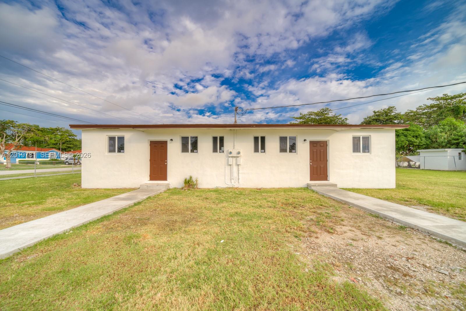 A single-story duplex with white stucco walls, two brown doors, and concrete walkways — 17727 SW 103rd Ave # 17727, Miami FL 33157, MIAMI, FL