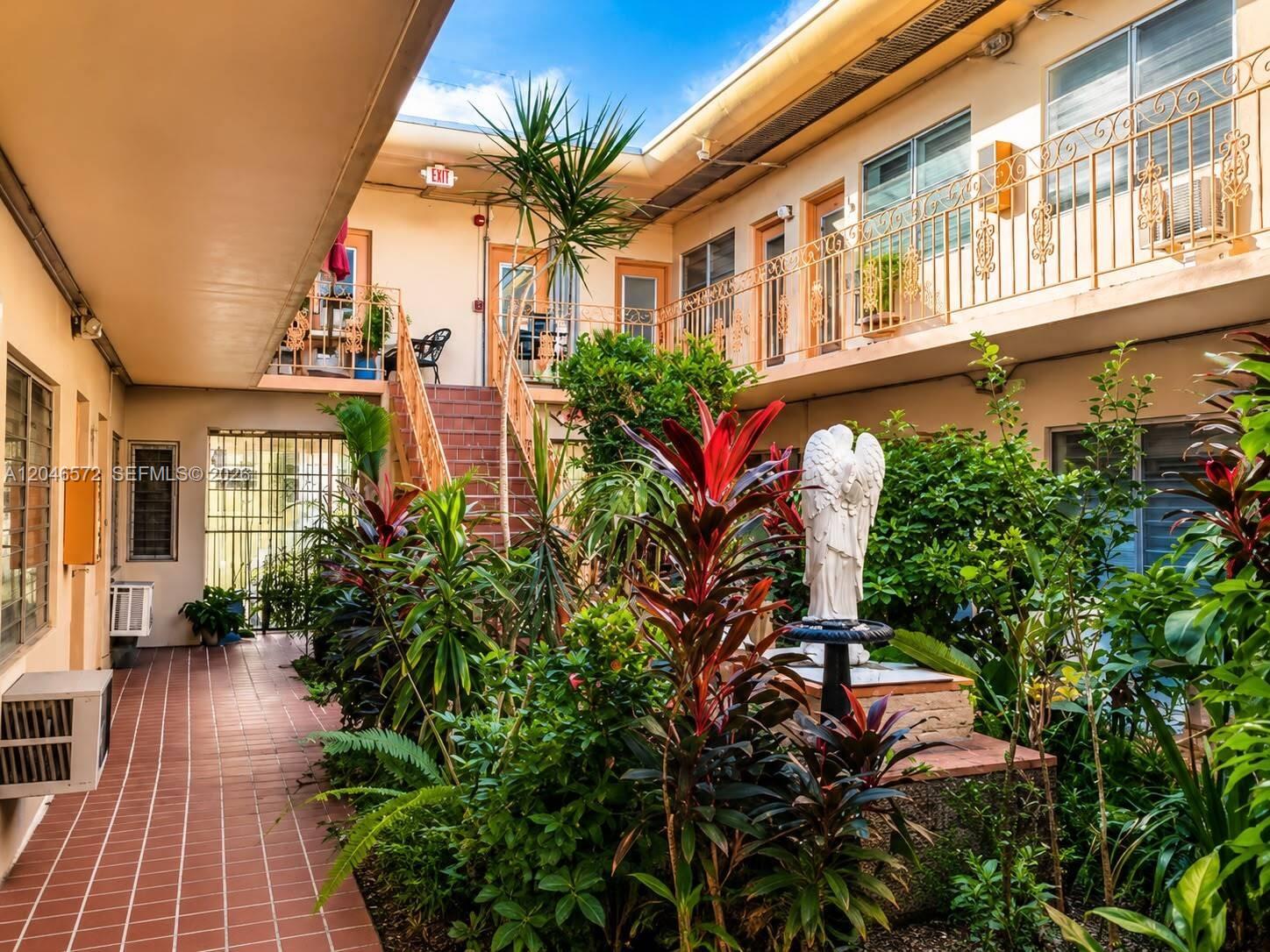 An outdoor courtyard features a central angel statue, lush tropical plants, and a tiled walkway — 1050 Pennsylvania Ave # A, Miami Beach FL 33139, MIAMI BEACH, FL