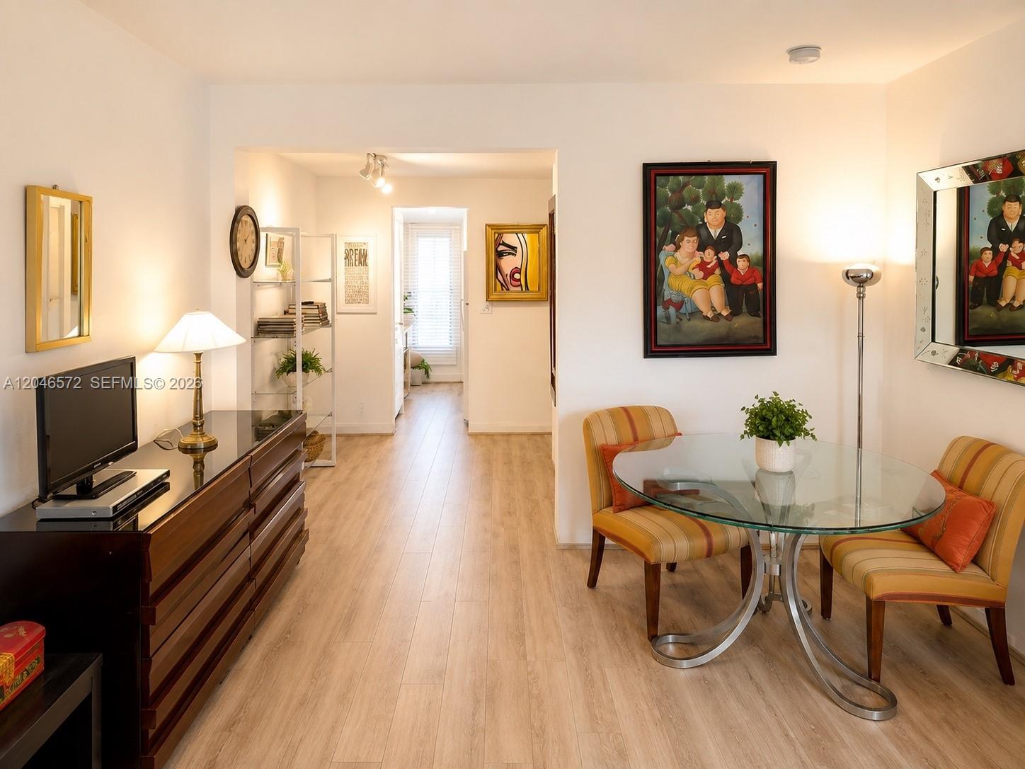 A dining area with a glass table and striped chairs sits beside a living space — 1050 Pennsylvania Ave # A, Miami Beach FL 33139, MIAMI BEACH, FL