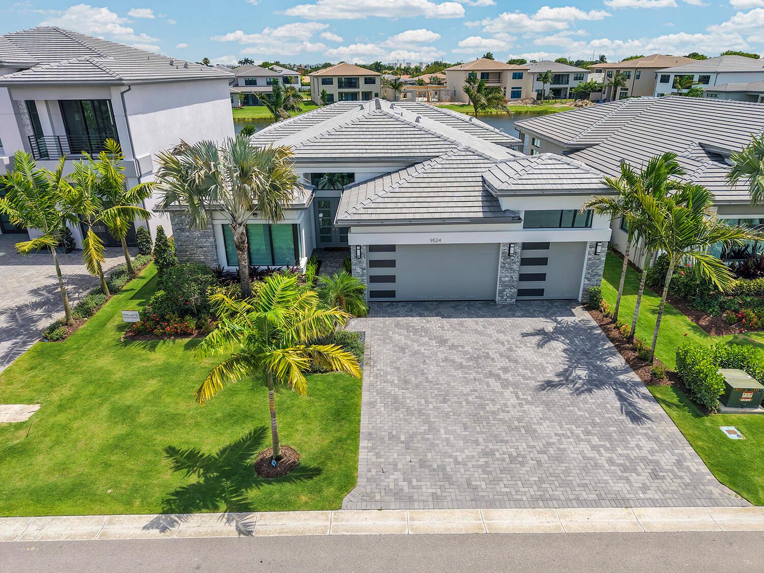 An aerial view of a modern single-story house with a gray tile roof and paver driveway — 9524 Riverside Park Drive, Boca Raton FL 33434, BOCA RATON, FL