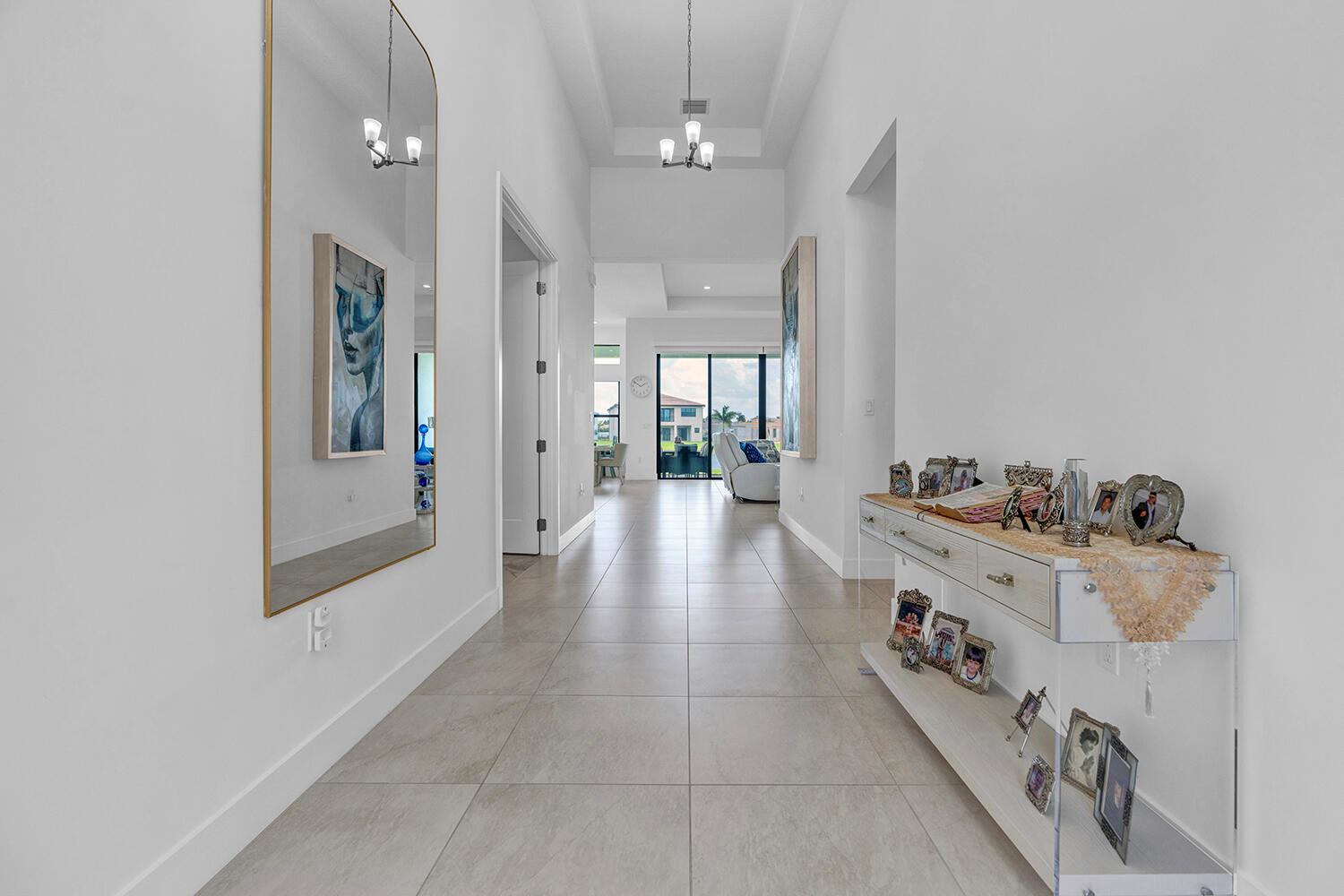A bright hallway features light tile flooring, a large wall mirror, and a console table — 9524 Riverside Park Drive, Boca Raton FL 33434, BOCA RATON, FL