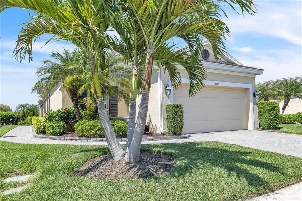 A single-story house with a beige stucco exterior, a two-car garage, and palm trees — 2615 VAREO COURT, CAPE CORAL, FL