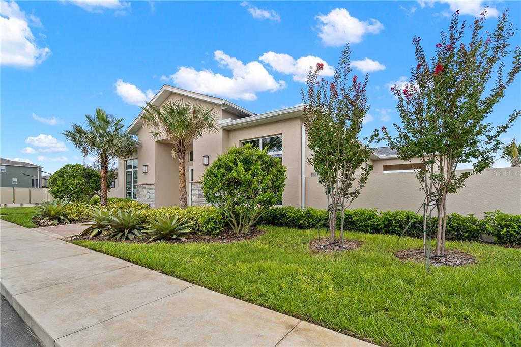 A beige single-story house features a stone-accented entryway, palm trees, and a manicured lawn — 1534 PLANK PLACE, DAVENPORT, FL