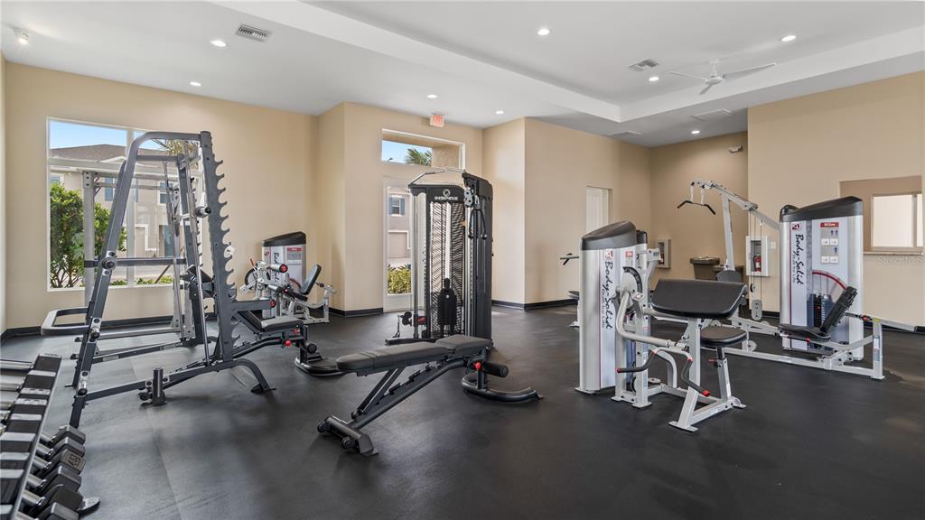 A gym room features various weight machines, a workout bench, and rubber flooring — 1534 PLANK PLACE, DAVENPORT, FL