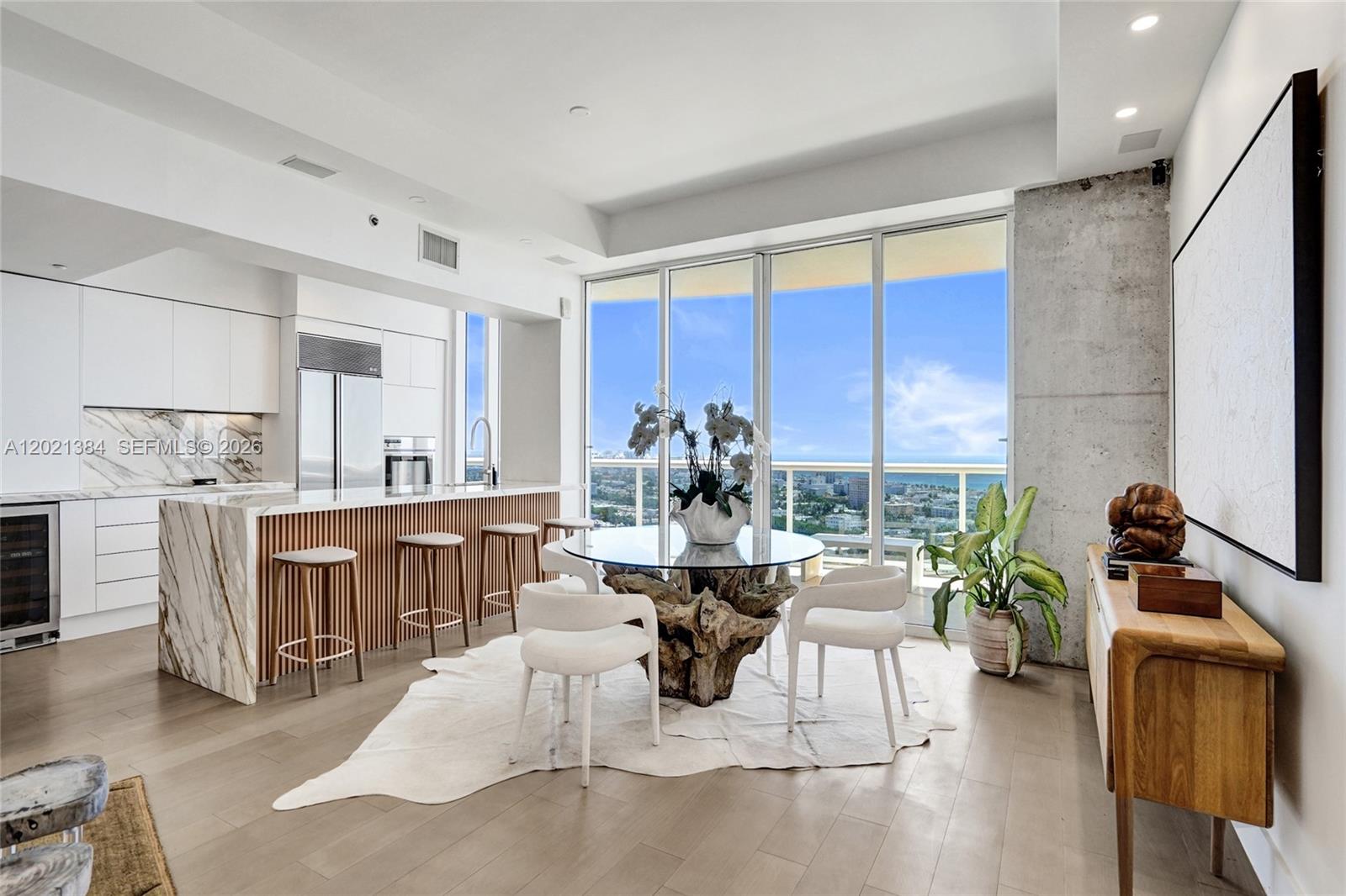 A modern kitchen and dining area features a marble island, glass table, and ocean views — 400 Alton Rd, Miami Beach FL 33139, MIAMI BEACH, FL