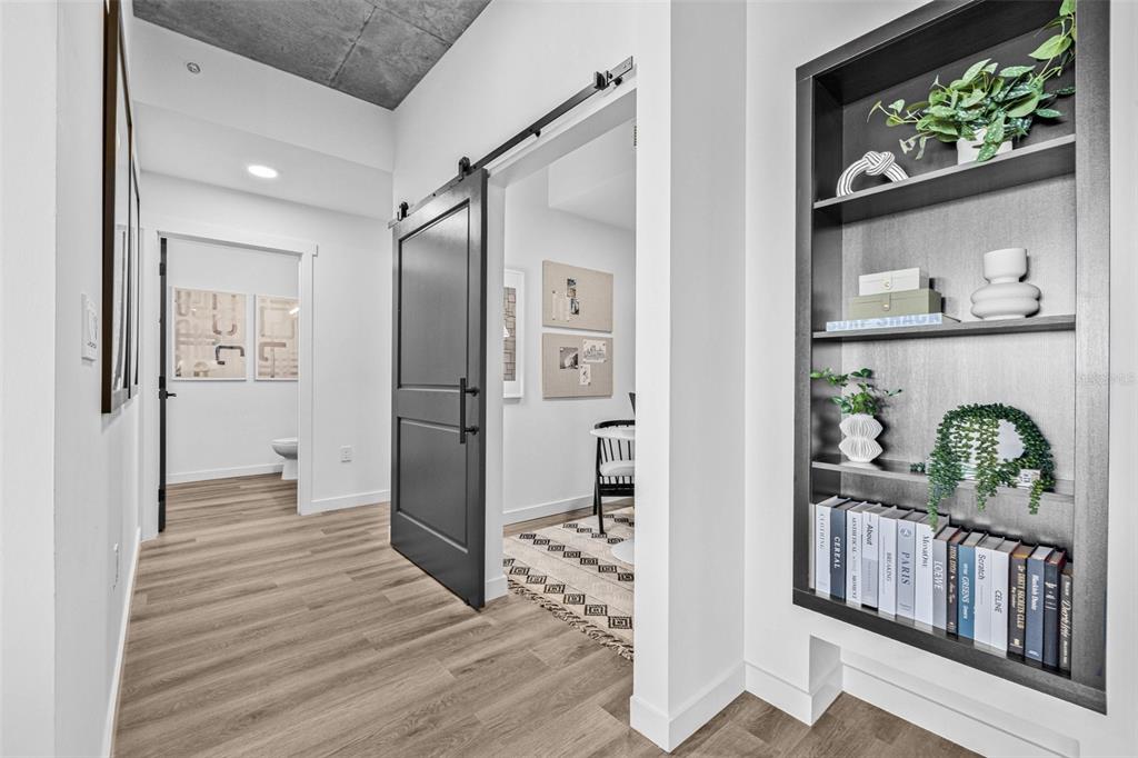 A hallway features light wood flooring, a black barn door, and a built-in display shelf — 221 MAIN STREET N UNIT B4-1115, ST PETERSBURG, FL