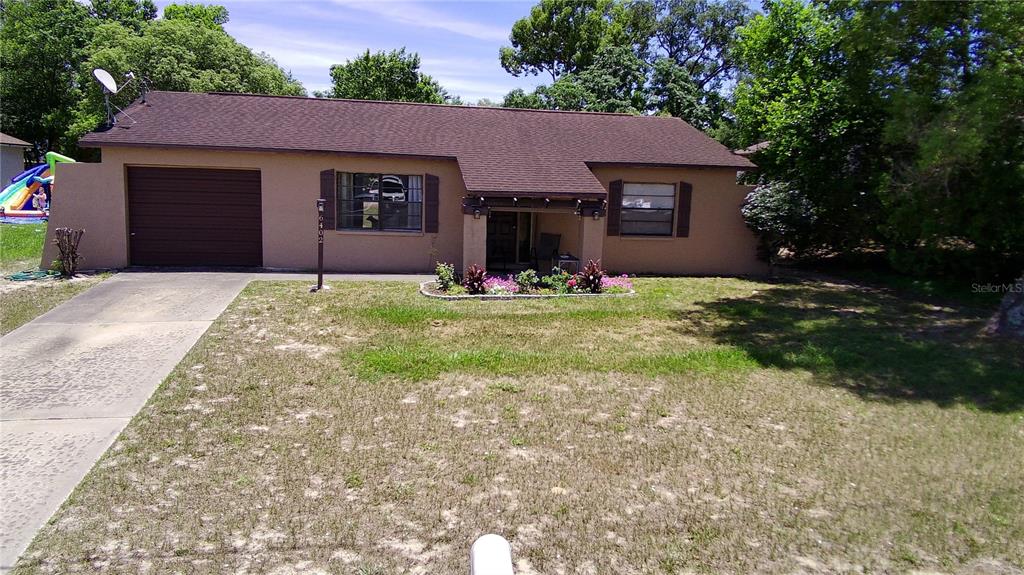 A single-story house with a brown roof, tan stucco exterior, and an attached garage — 6402 COVEWOOD DRIVE, SPRING HILL, FL