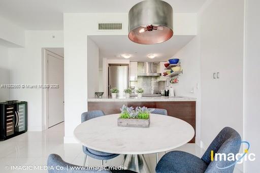 A dining area with a round white table and blue chairs sits before a kitchen — 720 NE 62nd St # 402, Miami FL 33138, MIAMI, FL