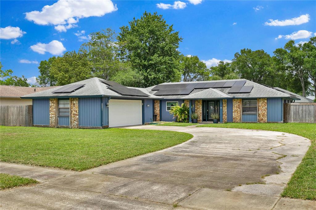 A blue single-story house with a stone facade, solar panels, and a concrete driveway — 969 GRAN PASEO DRIVE, ORLANDO, FL