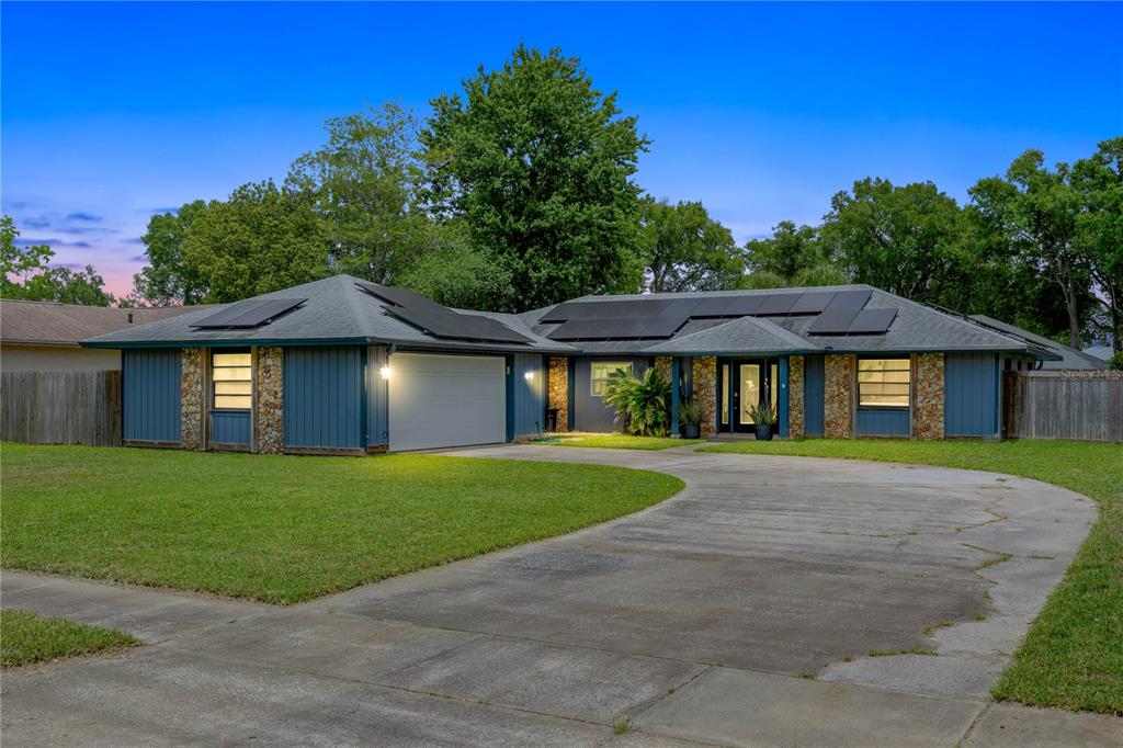 A single-story house with blue siding, stone accents, a two-car garage, and rooftop solar panels — 969 GRAN PASEO DRIVE, ORLANDO, FL