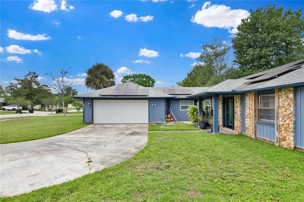 A blue house with a stone facade, a two-car garage, and solar panels on the roof — 969 GRAN PASEO DRIVE, ORLANDO, FL