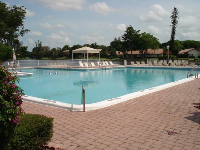 A rectangular swimming pool with a cabana and lounge chairs on a brick patio — 3740 Inverrary Drive # 1a, Lauderhill FL 33319, LAUDERHILL, FL
