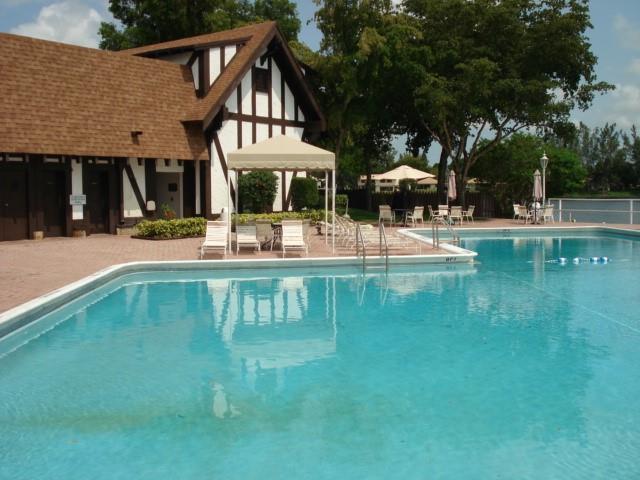 A swimming pool sits in front of a Tudor-style building with a patio and gazebo — 3740 Inverrary Drive # 1a, Lauderhill FL 33319, LAUDERHILL, FL