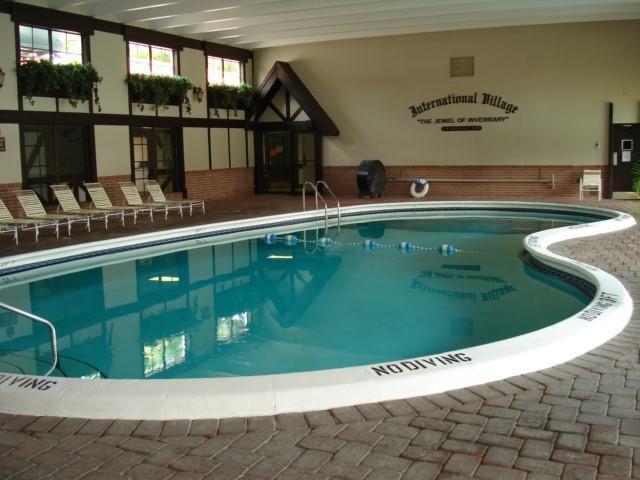 An indoor swimming pool with a white border is surrounded by a brick patio — 3740 Inverrary Drive # 1a, Lauderhill FL 33319, LAUDERHILL, FL