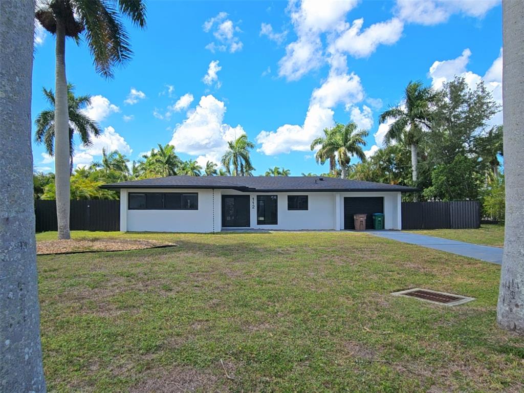A single-story white house with a dark roof, black trim, and a front-facing garage — 112 BAYSHORE DRIVE, CAPE CORAL, FL