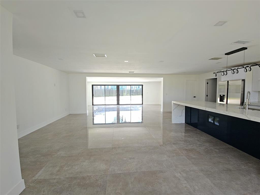 A modern, open-concept kitchen and living area with large light-colored floor tiles and white walls — 112 BAYSHORE DRIVE, CAPE CORAL, FL