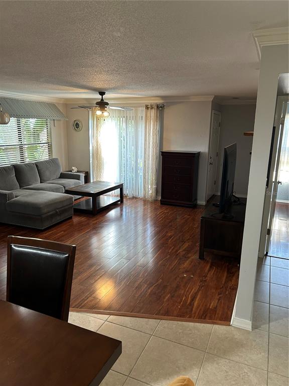 A living room features a gray sectional sofa, dark wood flooring, and a sliding glass door — 1505 LENNOX ROAD E UNIT 1505, PALM HARBOR, FL