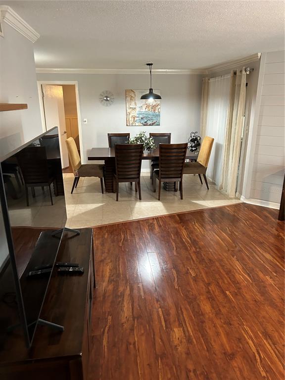 A dining area with a wooden table and chairs sits adjacent to a living room — 1505 LENNOX ROAD E UNIT 1505, PALM HARBOR, FL