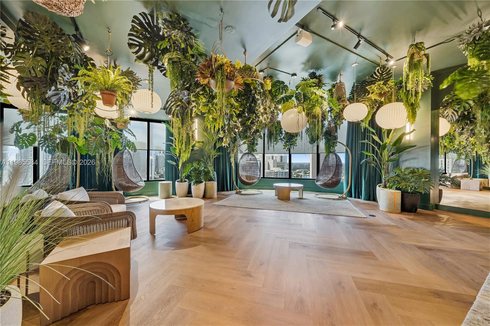 A lounge area features hanging plants, swing chairs, and herringbone wood floors with city views — 121 NE 5th # 2604, Miami FL 33132, MIAMI, FL