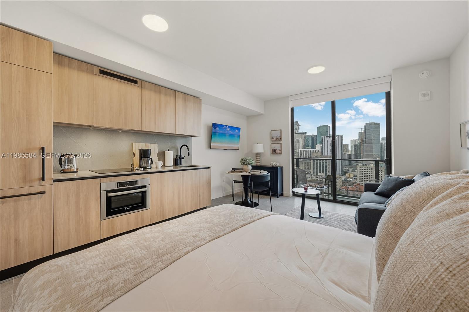 A studio apartment features a kitchenette with light wood cabinets and a city view balcony — 121 NE 5th # 2604, Miami FL 33132, MIAMI, FL