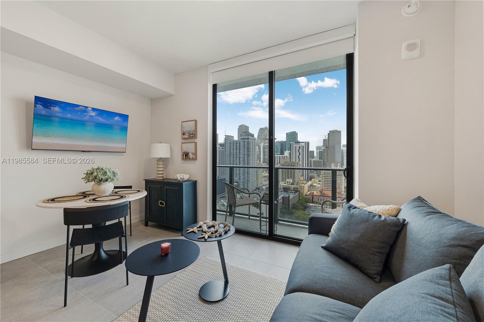 A living room features a sofa, dining area, and a balcony with a city view — 121 NE 5th # 2604, Miami FL 33132, MIAMI, FL