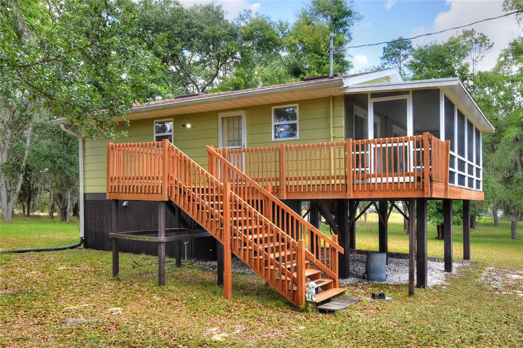 An elevated house with green siding, a wooden deck, and a screened-in porch — 1885 PFUNDSTEIN ROAD, LAKE WALES, FL