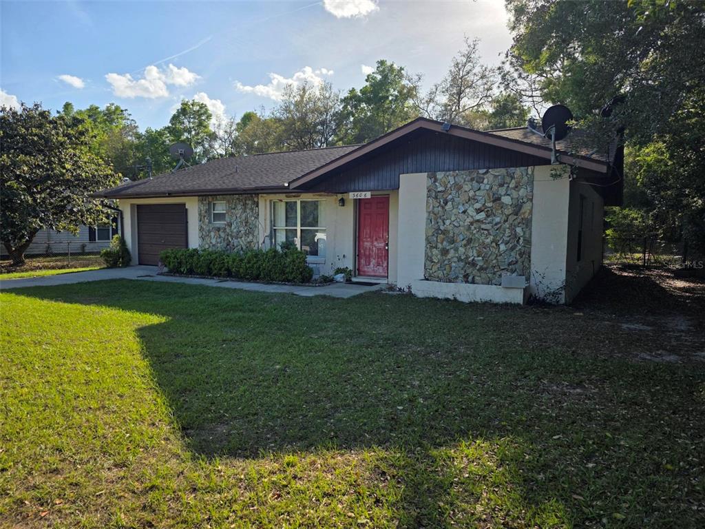 A single-story house with a stone facade, a red front door, and an attached garage — 3606 SW SUNNYDALE STREET, DUNNELLON, FL