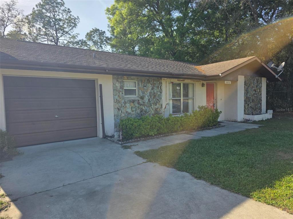 A single-story house features a brown garage door, stone facade, and a red front door — 3606 SW SUNNYDALE STREET, DUNNELLON, FL