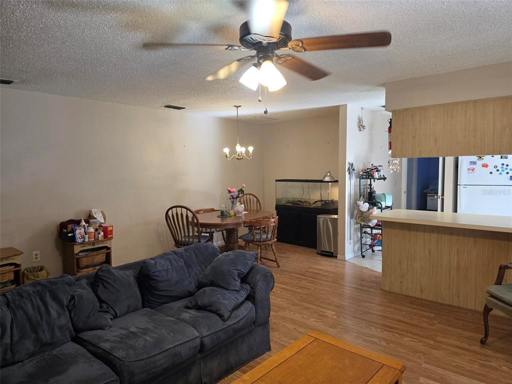 A living room with a dark sofa, dining area, and kitchen counter with wood cabinetry — 3606 SW SUNNYDALE STREET, DUNNELLON, FL