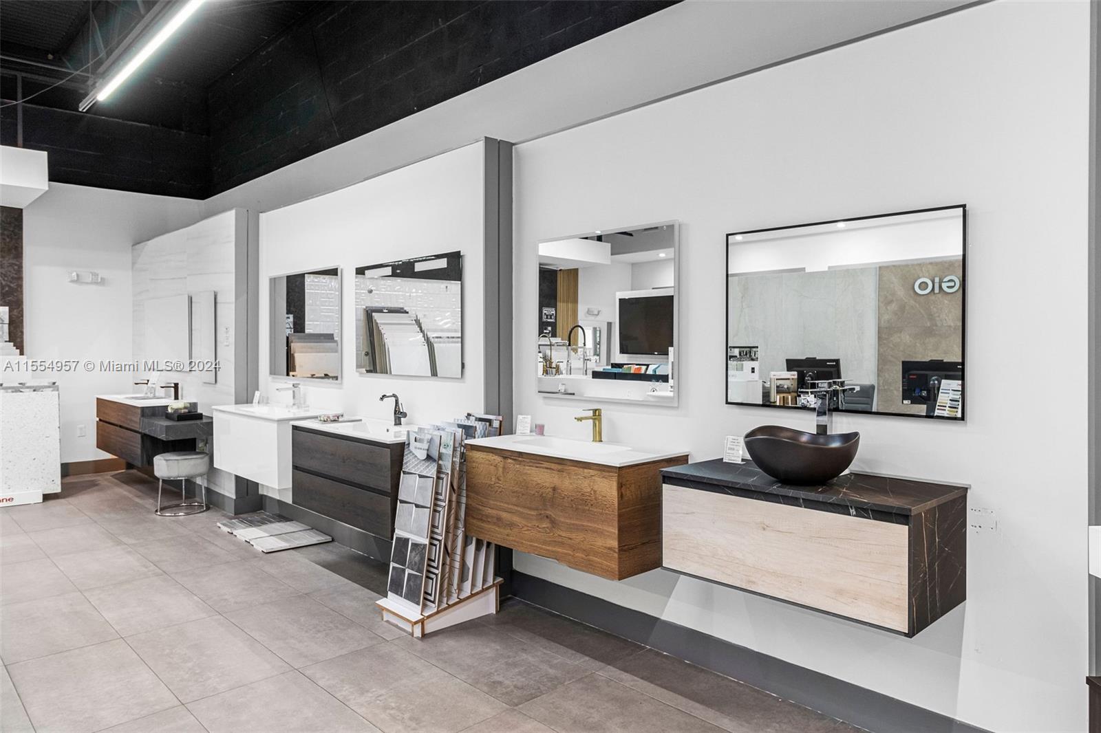 A showroom displays several modern wall-mounted bathroom vanities with various sinks, countertops, and mirrors — Bath Vanities/Accessories and Flooring, Doral FL 33122, DORAL, FL