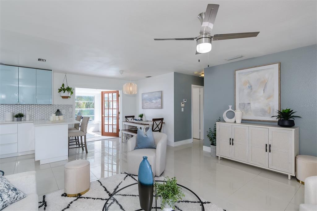 An open-concept living room and kitchen featuring white cabinetry, tile flooring, and a ceiling fan — 1435 77TH AVENUE N, ST PETERSBURG, FL