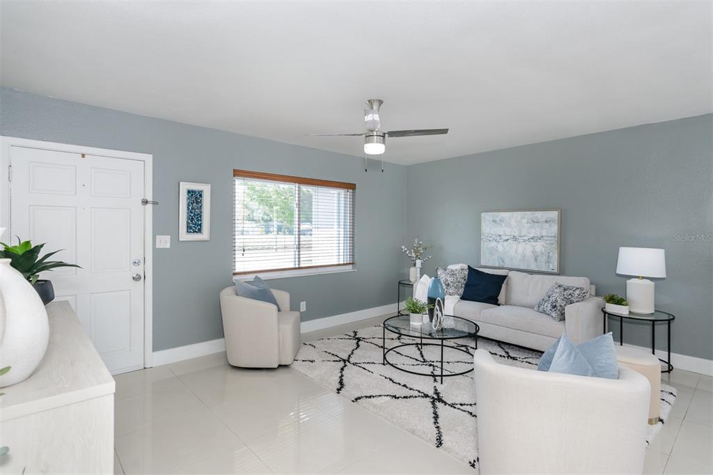 A living room features light blue walls, a white sofa, two armchairs, and tile flooring — 1435 77TH AVENUE N, ST PETERSBURG, FL