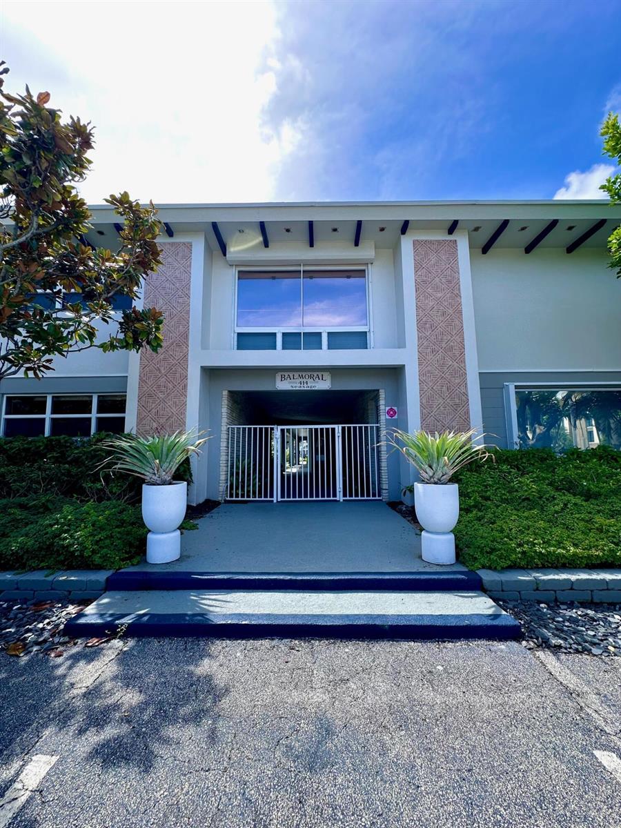 The exterior of a two-story apartment building features a gated entrance with two large potted plants — 414 Seasage Drive # 0030, Delray Beach FL 33483, DELRAY BEACH, FL