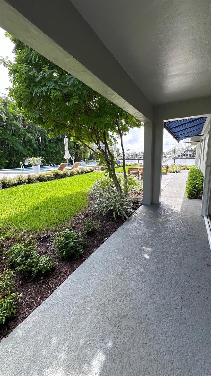 A covered patio overlooks a grassy lawn, a swimming pool, and a waterway with stairs — 414 Seasage Drive # 0030, Delray Beach FL 33483, DELRAY BEACH, FL