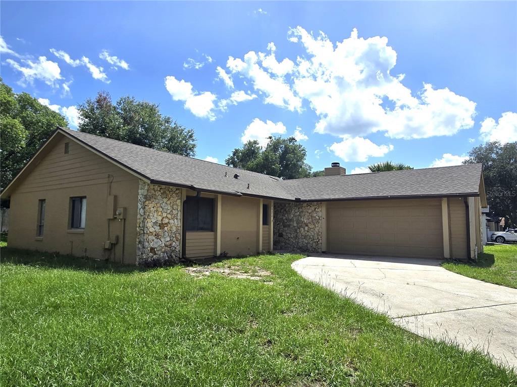 A single-story house with tan siding, stone accents, a two-car garage, and a concrete driveway — 8422 MARGARITA DRIVE, ORLANDO, FL