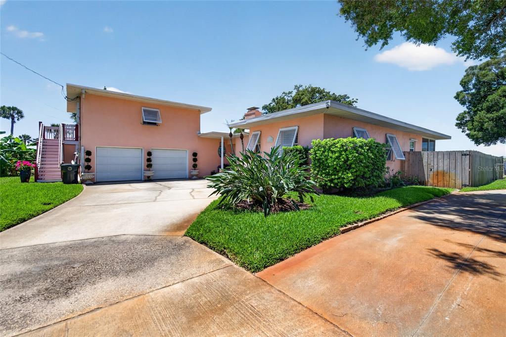A peach-colored house with a two-car garage, a concrete driveway, and a wooden fence — 1209 N HALIFAX AVENUE, DAYTONA BEACH, FL