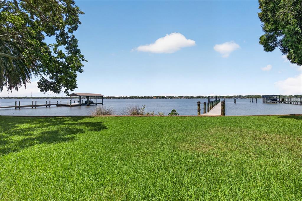 A grassy lawn overlooks a body of water with two private boat docks — 1209 N HALIFAX AVENUE, DAYTONA BEACH, FL
