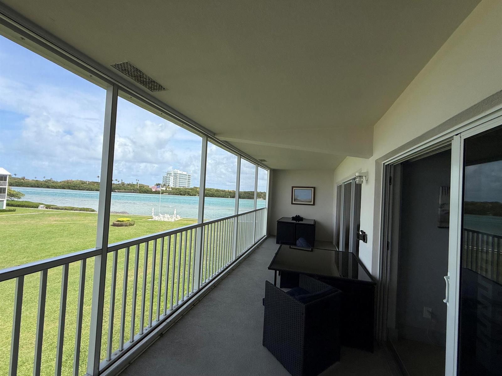 A screened-in balcony overlooks a grassy lawn and a body of water — 100 Waterway Road # E305, Tequesta FL 33469, TEQUESTA, FL