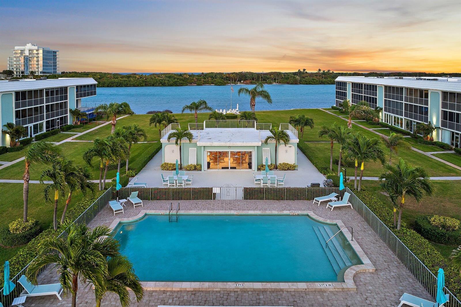 An aerial view of a swimming pool, clubhouse, and two apartment buildings overlooking a waterway — 100 Waterway Road # E305, Tequesta FL 33469, TEQUESTA, FL