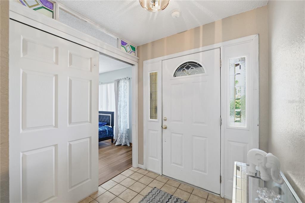 An entryway with tile flooring, a white front door with sidelights, and a sliding door — 9470 MONTEBELLO LANE, SPRING HILL, FL